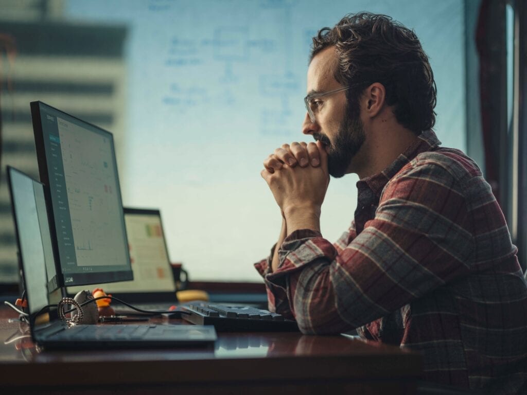Person working in front of a Lenovo ThinkPad with multiple monitors