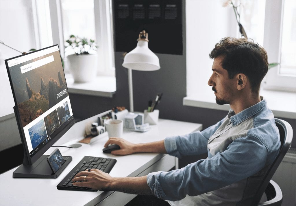 The new Lenovo L27e-30 Monitor seen in use by a person sitting in profile with keyboard and mouse