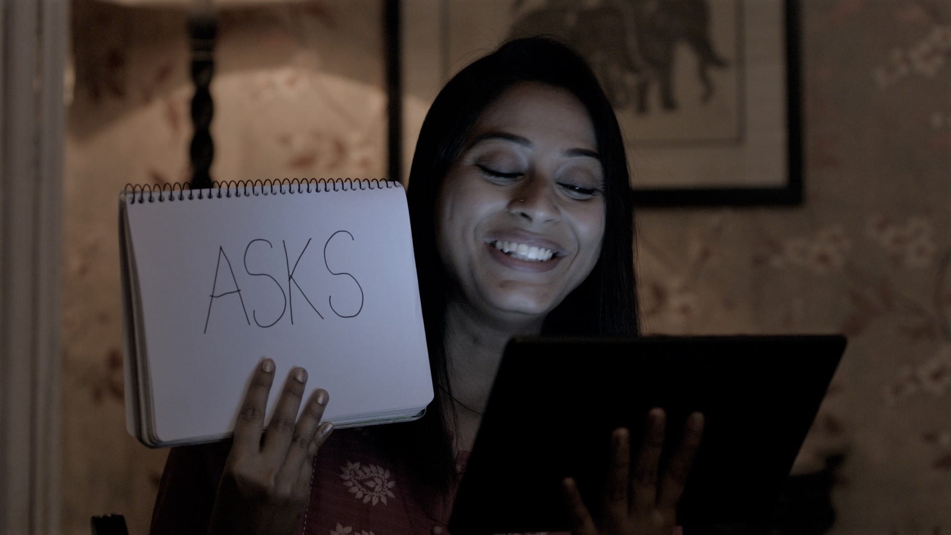 Teacher holding up a pad with text to a tablet, working virtually with students