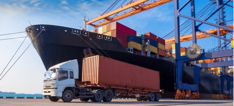 Large truck in front of cargo ship.