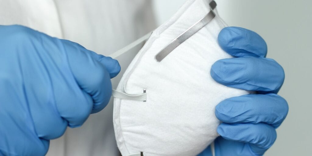 Medical mask held by gloved hands