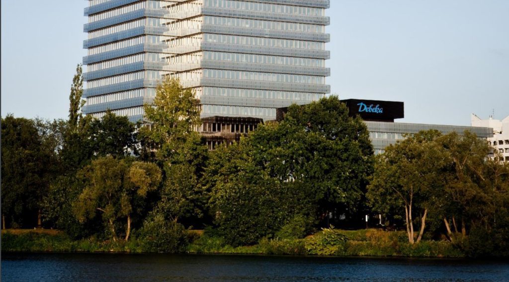 Debeka building behind tree line in front of river