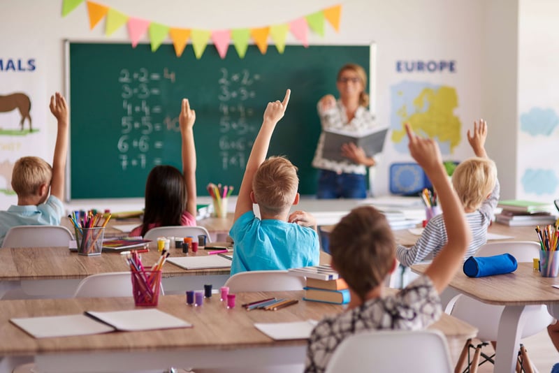 Students in a classroom raising their hands