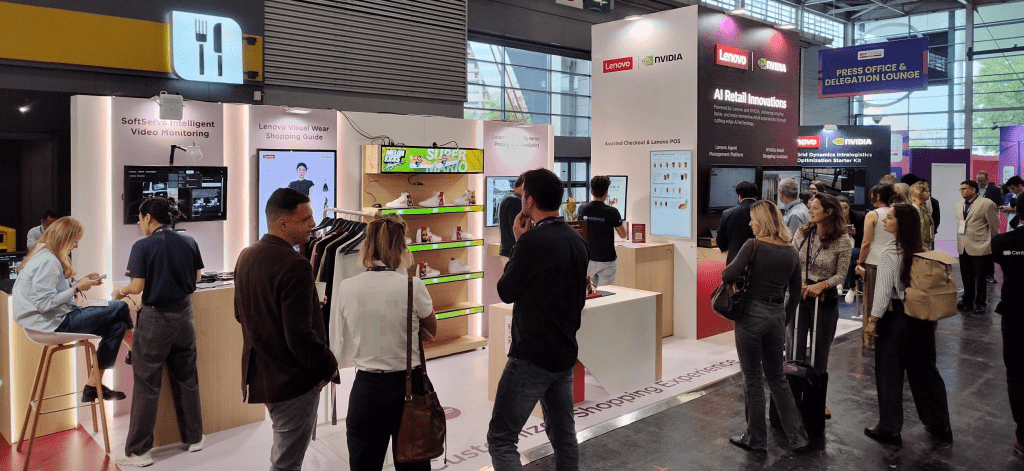Small groups of professionals standing at the Lenovo booth in an exhibition hall at an event