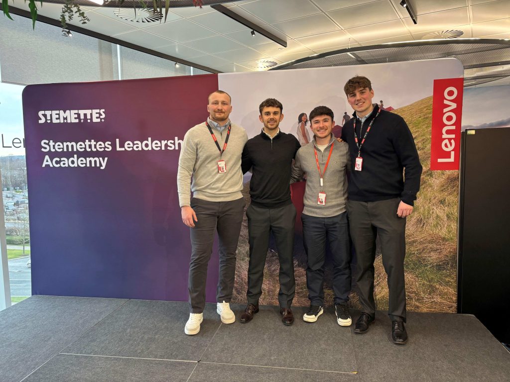 Lenovo employees stood in a row with arms around each other in front of an Lenovo Academy sign